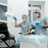 Dentists in a clinic prepare for a dental procedure with patient seated, showcasing teamwork.