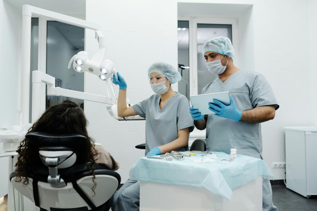 Dentists in a clinic prepare for a dental procedure with patient seated, showcasing teamwork.