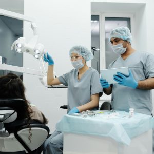 Dentists in a clinic prepare for a dental procedure with patient seated, showcasing teamwork.