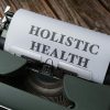 Close-up of a vintage typewriter with 'Holistic Health' on paper, representing wellness.