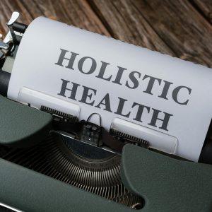 Close-up of a vintage typewriter with 'Holistic Health' on paper, representing wellness.