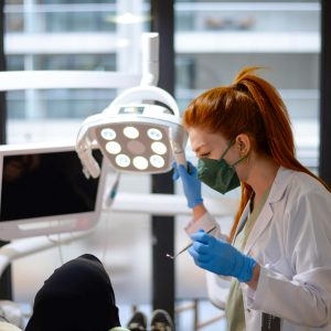A female dentist in a modern clinic performing a dental procedure on a patient.