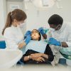 Two dental professionals treat a patient in a modern clinic setting.