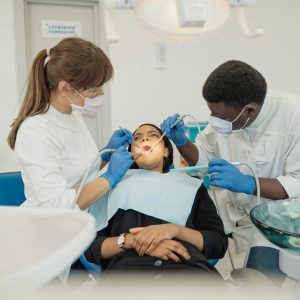 Two dental professionals treat a patient in a modern clinic setting.